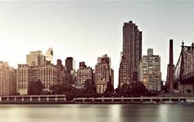 A city skyline with buildings and water in the foreground.