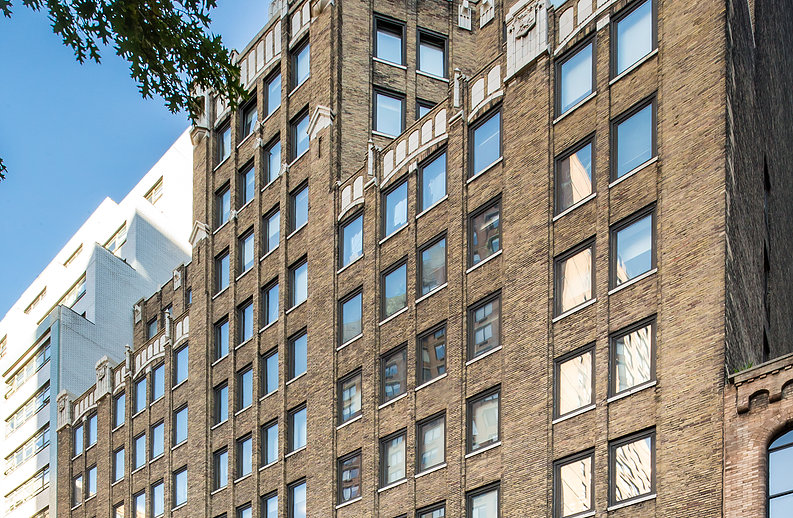 A building with many windows and a tree in front of it.