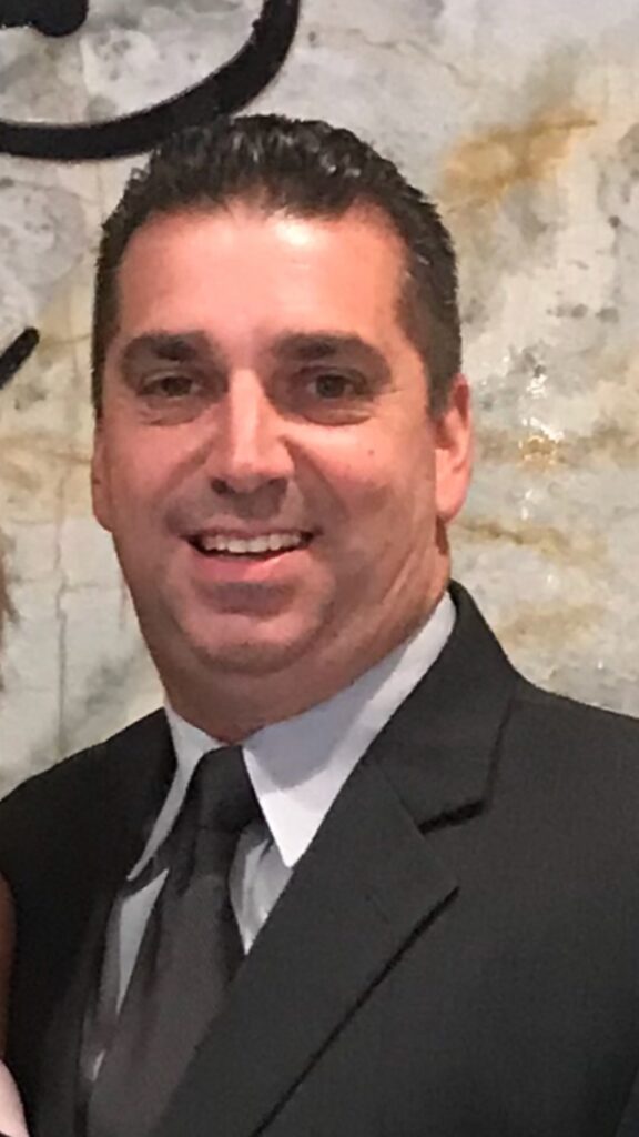 A man in a suit and tie smiling for the camera.